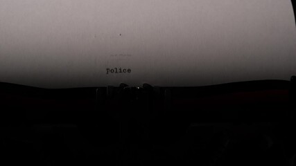 Close up view of a vintage typewriter typing the word police on an old sheet of paper, symbolizing crime investigation, journalistic reporting, and the legal system