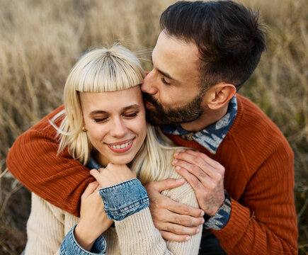 Couple enjoying a relaxing moment together on the grass and taking a selfie with a mobile phone camera during a sunny day in a field - Powered by Adobe