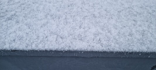 Snow covers a flat surface creating a peaceful winter scene in a quiet neighborhood