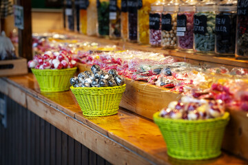 Many sweets and lollipops for sale in baskets at a stall at the Christmas market or holiday fairground, copy space, selected focus