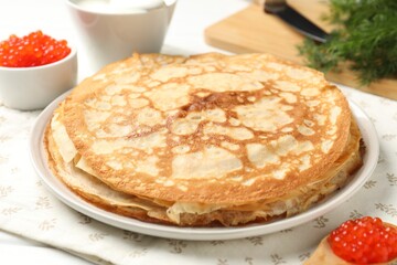Tasty crepes with red caviar, sour cream and dill on table, closeup