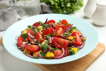 Delicious salad with lentils and vegetables on white table, closeup