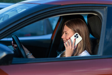 Young woman talking on smartphone while driving a car