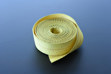 Rolled yellow tie-down strap on dark surface