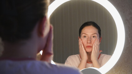 A young girl makes up and looks in the mirror