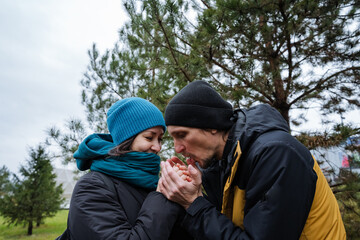partner warming hands with warm breath, cupped palms and knit gloves, intimate caring gesture against chilly air, close composition highlighting facial warmth and seasonal outerwear