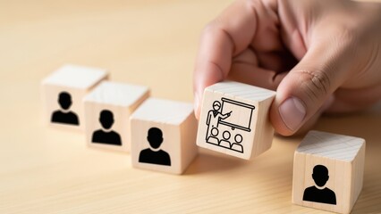 Hand placing a wooden block with a presentation icon onto a line of blocks with person icons