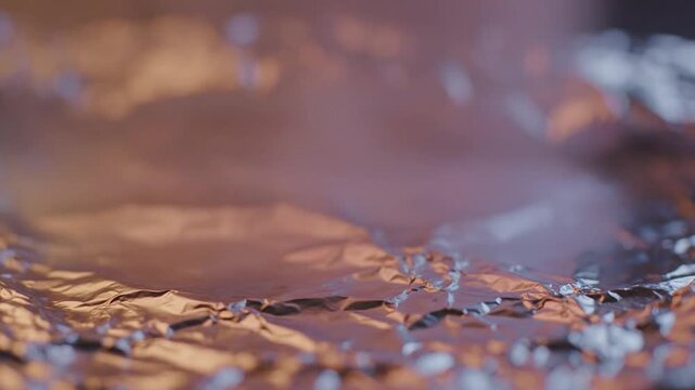 Crumpled foil reflecting warm and cool light with soft haze and bokeh