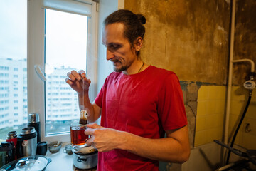 gentle domestic morning, man prepares tea in cozy kitchen, small apartment setting with steaming tea ritual, quiet moment of man making tea in modest home during peaceful hours