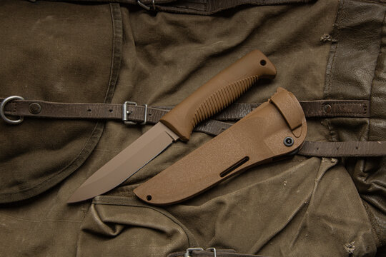 Military-style fixed blade knife and sheath on fabric.