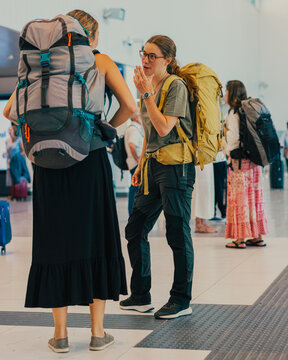 Young adult women backpackers talking at airport before journey