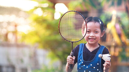 A cute Asian girl holds a badminton racket while exercising in the evening.