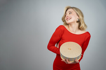 Young beautiful woman in festive red dress opens gift box. Celebrating Christmas. New Year. Winter...