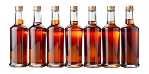 A row of six glass bottles filled with a dark amber liquid against a black background in a studio shot on transparent background