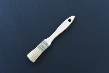 Flat paintbrush resting on dark textured surface