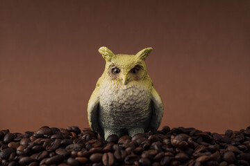 Creative surreal owl and coffee beans composition against brown background. Minimal coffee concept....