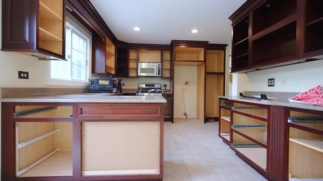 Removal of old kitchen. Kitchen undergoing renovation. Upper cabinets remain installed while lower cabinets have been removed, revealing an open construction space.