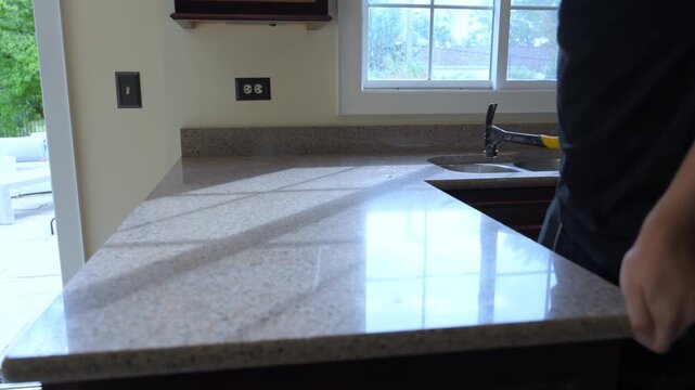 Contractor removes old kitchen countertop during a home renovation project. Worker swinging hummer, lifts and detaches the laminate counter, preparing for new installation.