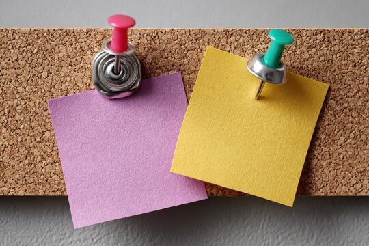 Cork board with colorful push pins and yellow note, perfect for leaving messages and reminders in an office or home setting