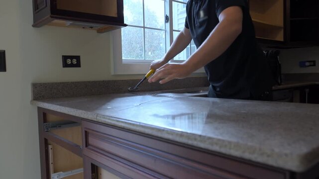 Contractor removes an old kitchen countertop during a home renovation project. The worker lifts and detaches the laminate counter, preparing for new installation.