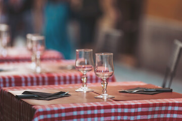 Tables set with glasses and napkins ready for dining at an outdoor cafe in a bustling street during a sunny afternoon in spring
