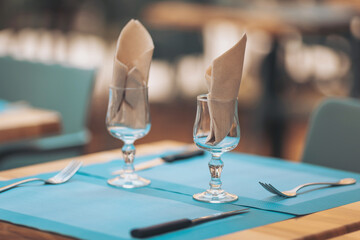 Elegant dining setup with folded napkins in glassware on a blue tablecloth at a cozy restaurant