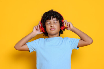 Portrait of little boy with headphones on yellow background