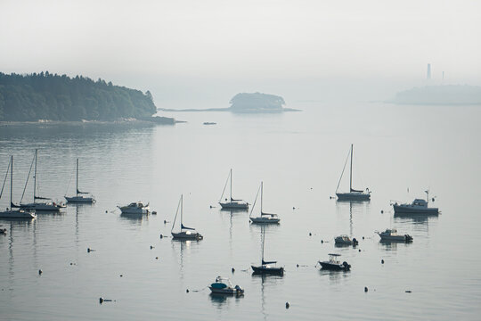 A foggy morning envelopes sailboats in the harbor in the Casco Bay next to the Eastern Promenade, Portland, Maine