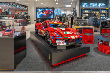 Naklejka premium Germany Berlin December 3, 2025. Large LEGO Ferrari race car is showcased in the menswear department. Colorful brick model draws attention amid racks of clothing.