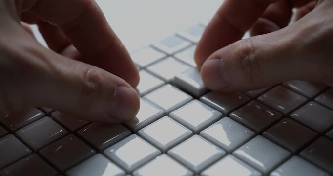 Hand arranging white mosaic tiles close up construction detail.