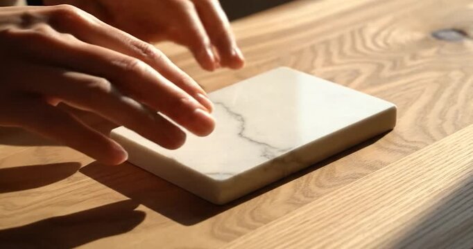Designer comparing marble stone sample with wood surface in bright light.