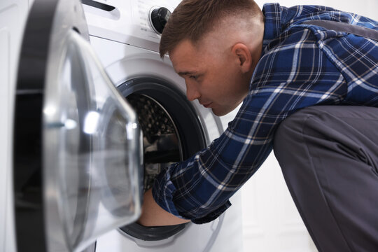 Repairman fixing broken washing machine at home