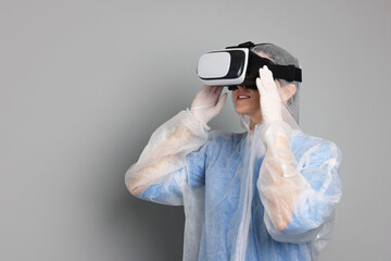 Modern technology. Doctor using virtual reality headset on grey background. Space for text