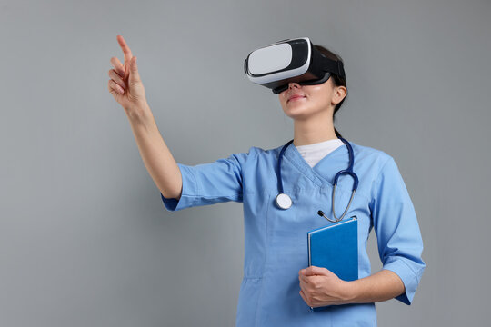 Modern technology. Doctor in headset using virtual screen on grey background - Powered by Adobe