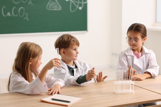 Group of children with test tubes doing chemical experiment at desk in class. Little scientists - Powered by Adobe