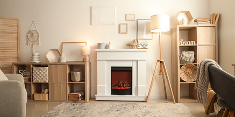 Fototapeta premium Interior of cozy living room with fireplace, shelving units and lamps