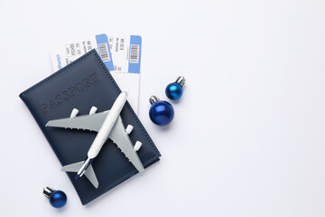 Naklejka premium Christmas vacation. Passport with tickets, plane model and ornaments on white background, flat lay. Space for text