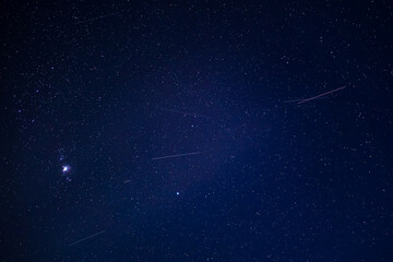 Starry night sky with meteor shower and orion constellation
