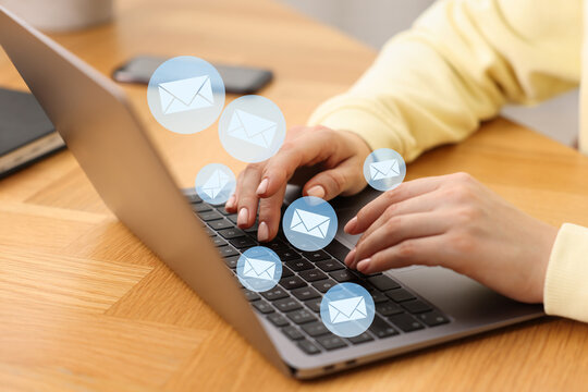 Woman sending or receiving email on laptop at table, closeup. Letters flying out of screen