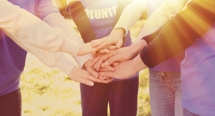 Group of volunteers stacking hands outdoors on sunny day, closeup. Banner design