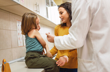 Fototapeta premium Mother encouraging child during vaccination in doctors office.