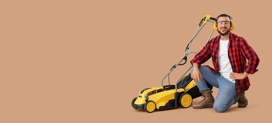 Young man with modern lawn mower on beige background with space for text
