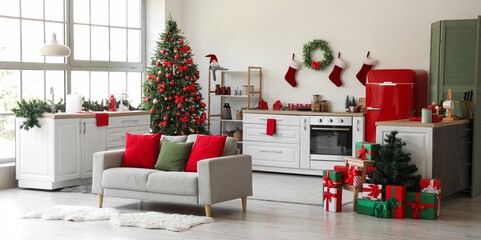 Interior of light kitchen with Christmas trees, counters and sofa