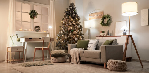 Interior of festive living room with grey sofa, Christmas tree and glowing lamps at evening