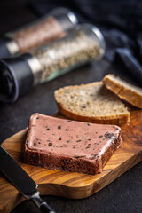 Liver pate with cranberries on wooden cutting board.