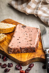 Liver pate with cranberries on wooden cutting board.