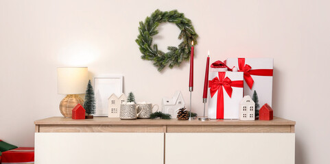 Candles, Christmas decor and gifts on chest of drawers in interior of living room