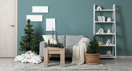 Interior of living room with Christmas trees, sofa and burning candles on table