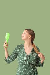 Beautiful young woman with handheld mini fan on green background