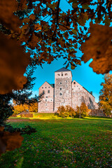Vertical Photograph of Historic Turku Castle Surrounded by Vibrant Autumn Foliage.